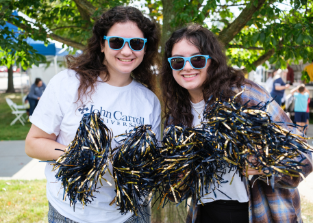 two female students waving ִ˰appԼ pom poms at homecoming game
