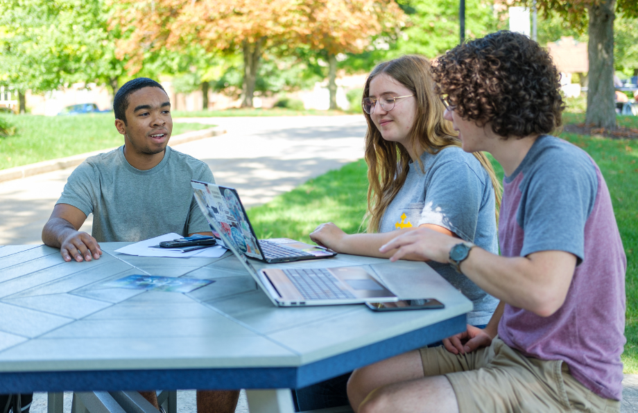 three ִ˰appԼ students meeting at a table on the quad during spring